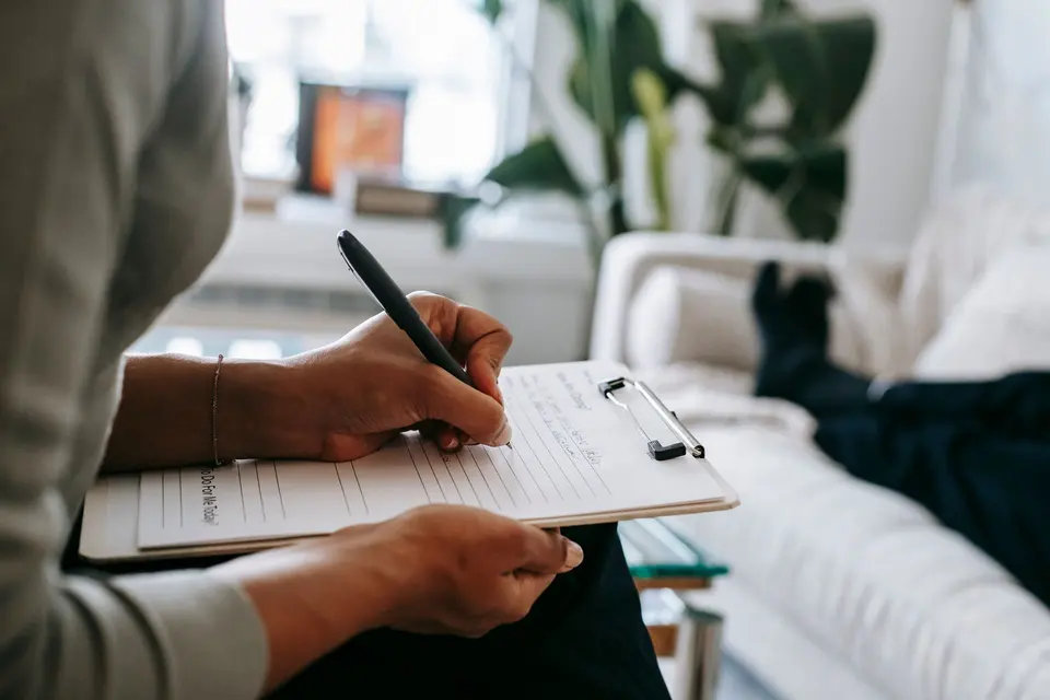 Clinician filling in an intake form on a clipboard during a first visit