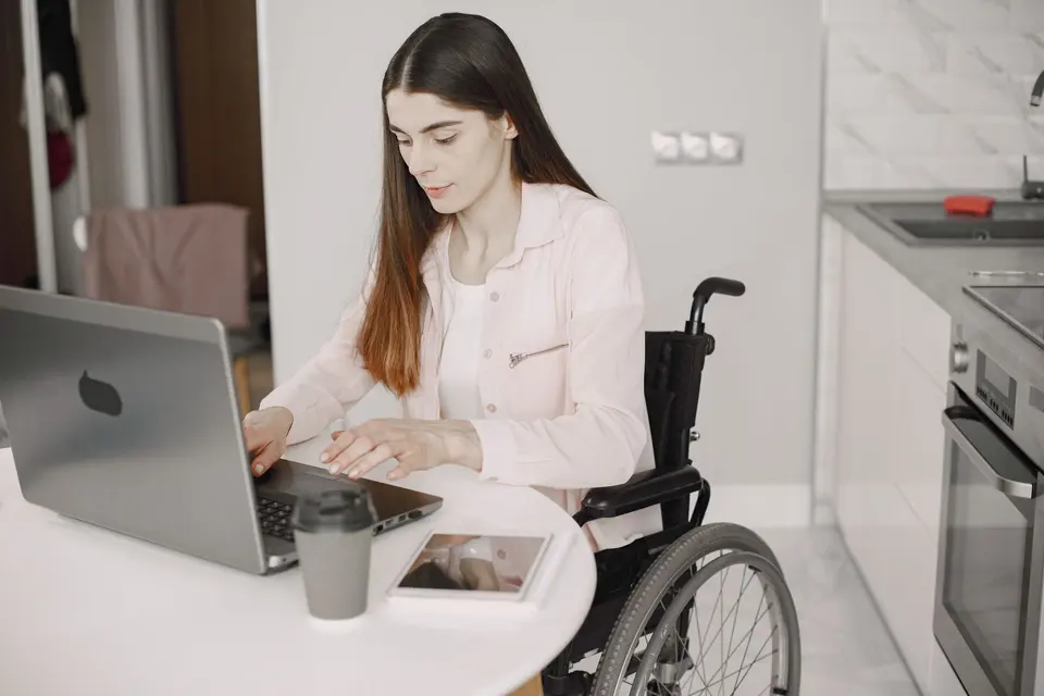 Woman using a wheelchair working on a laptop at her desk